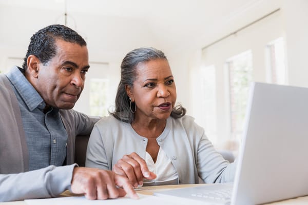 Two residents engaged with a laptop in a bright room