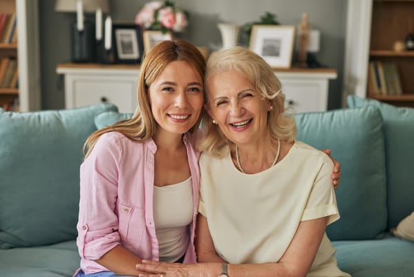 Smiling woman and elderly lady in cozy living room