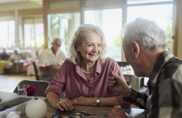 Residents engaged in a puzzle activity with smiles.