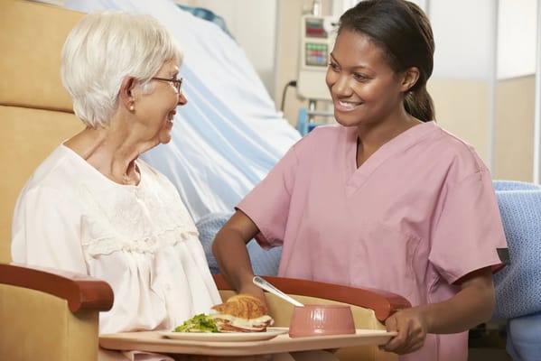 A caregiver serving food to a senior resident in a care setting