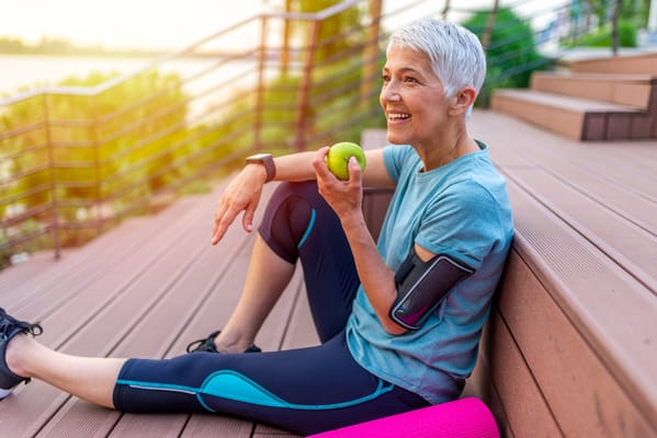 Active senior woman enjoying an apple outdoors