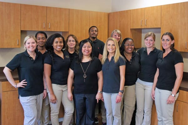 Staff members posing in a bright facility kitchen