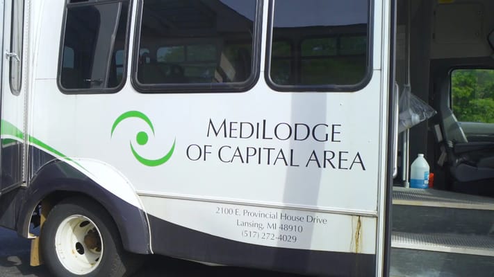 Facility transport bus with logo and contact information