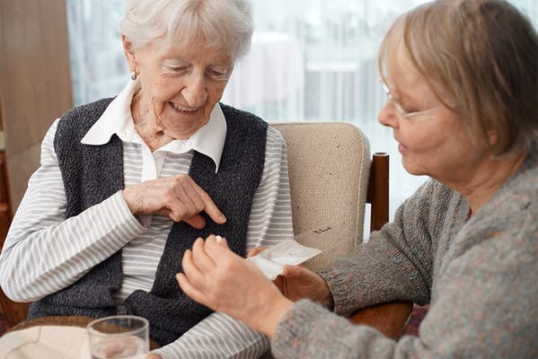 Two elderly women engaged in conversation indoors