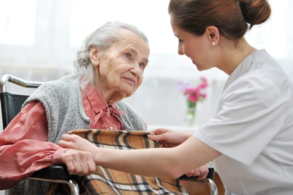 Caregiver assisting an elderly woman in a cozy interior setting