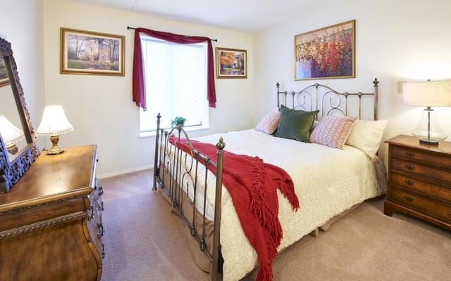 A cozy bedroom with a bed, dresser, and window.