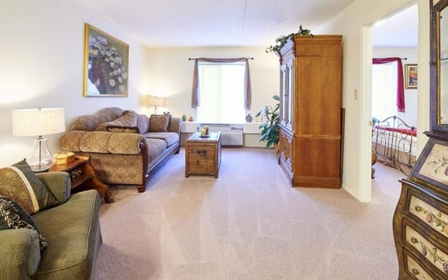 A cozy living room featuring a sofa, armchairs, and a wooden cabinet.