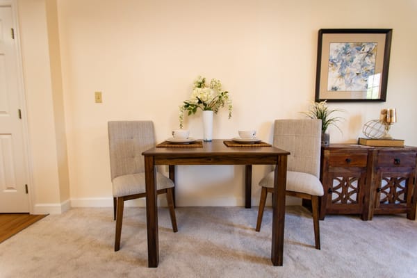 Dining table with two chairs, bowls, and a decorative flower arrangement