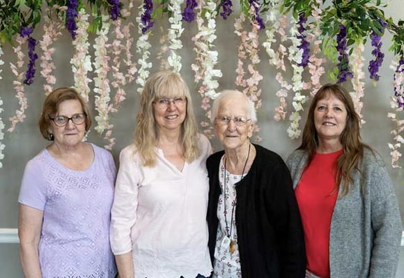 Four residents posing together in a decorated indoor space