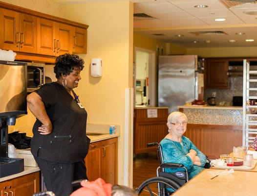 Staff member engaging with a resident in a dining area