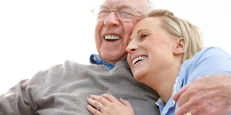 A senior man and a young woman smiling together