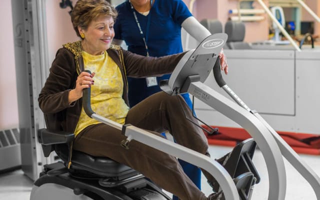 Resident exercising on a recumbent bike with staff assistance