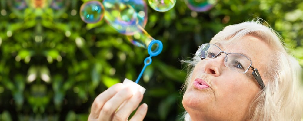Senior woman blowing bubbles in a garden