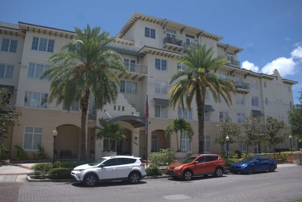 Exterior view of a senior living facility with palm trees