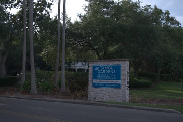 Sign for Tampa Gardens Senior Living surrounded by greenery