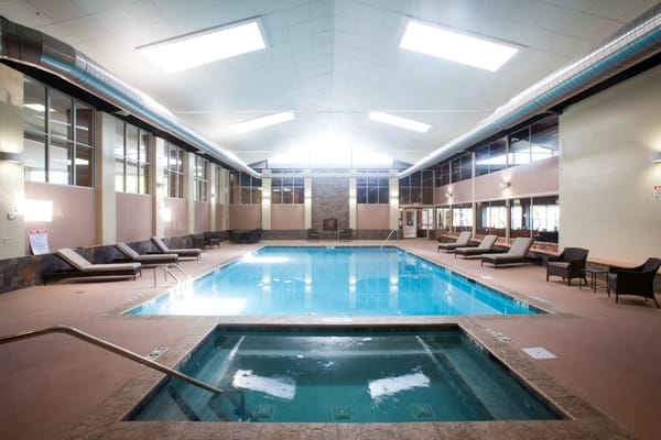 Indoor pool area with lounge chairs and hot tub