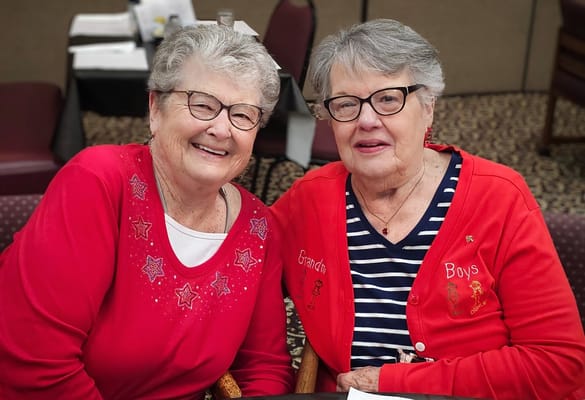 Two smiling residents in matching red cardigans