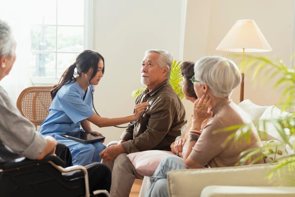 Caregiver examining a senior resident in a common area