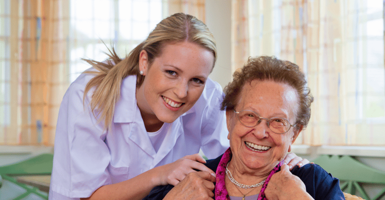Staff member smiling with a resident in a cozy interior