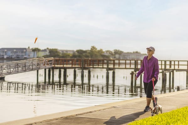 A woman walking her dog along a waterfront path