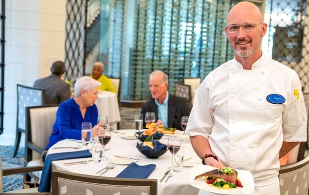 Chef serving a meal in the dining room with residents enjoying
