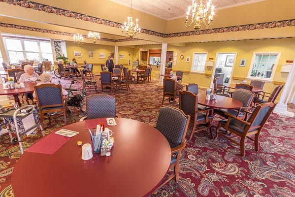 Bright dining room with residents and tables