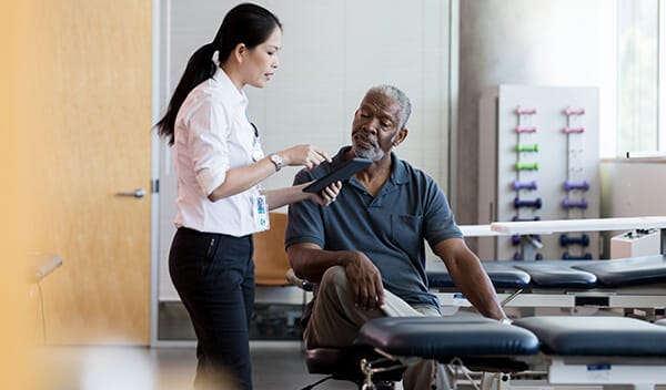A staff member helping a resident in a therapy room