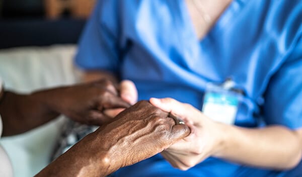 A caregiver holding a resident's hand