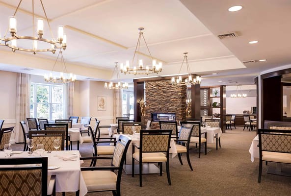 Elegant dining room setup with chandeliers and stone wall