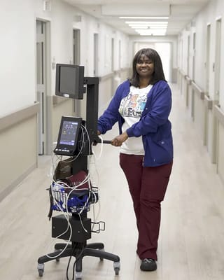 Staff member assisting with medical equipment in a hallway