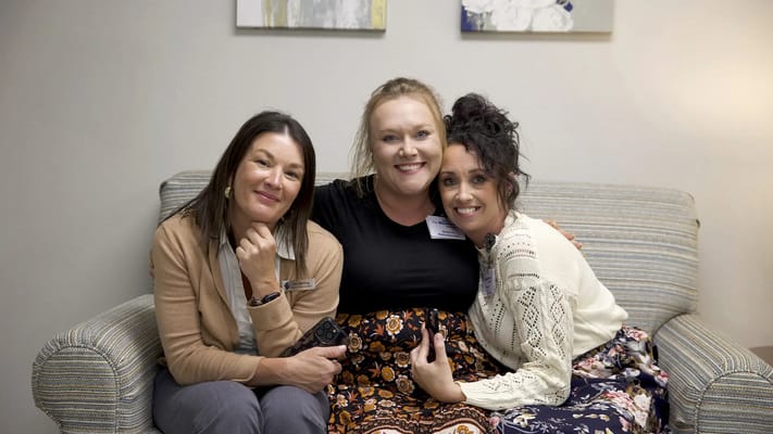 Three staff members smiling on a couch in a common area