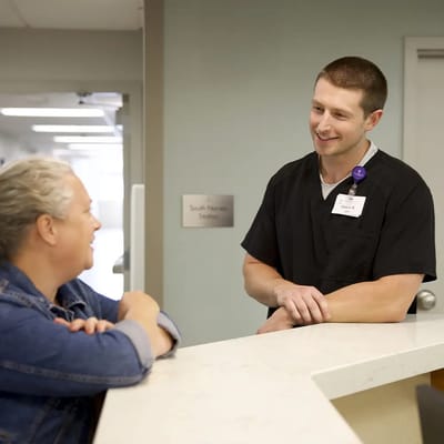 A staff member talking with a resident at the reception desk