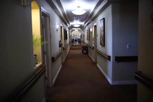 A hallway in an assisted living facility with a resident and staff member