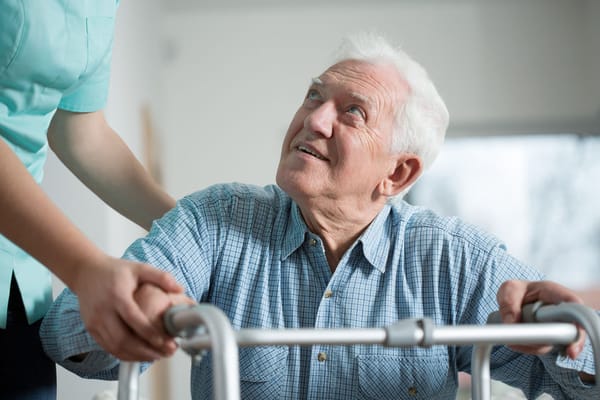Staff assisting a senior man with a walker