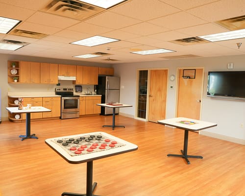 Bright activity room with game tables and kitchen area