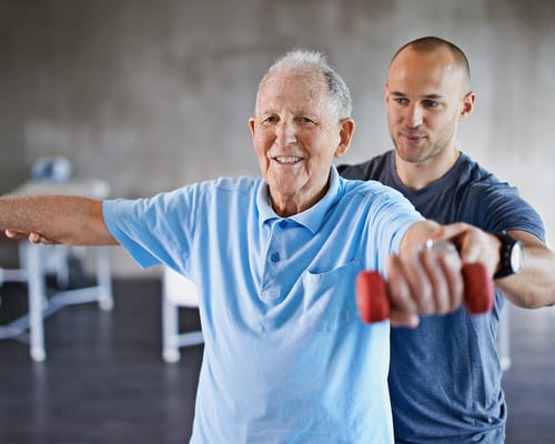 An older man participating in an exercise session with a trainer