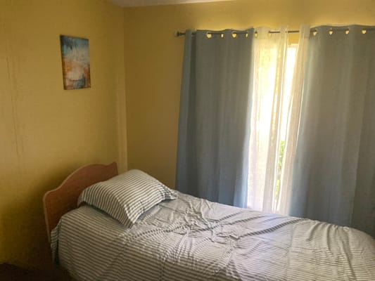 A simple bedroom setup with a bed and curtains