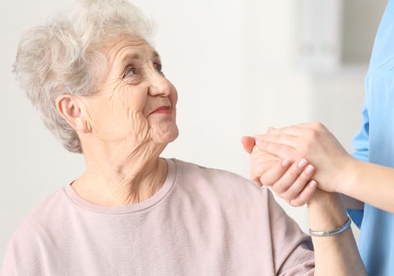 Caregiver holding hands with senior resident