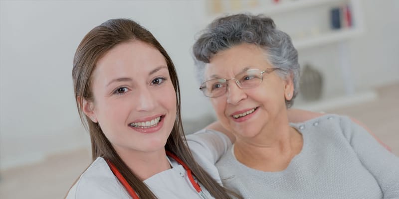 Nurse and resident smiling together in an indoor setting