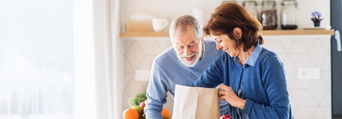 Two seniors preparing groceries together in a kitchen