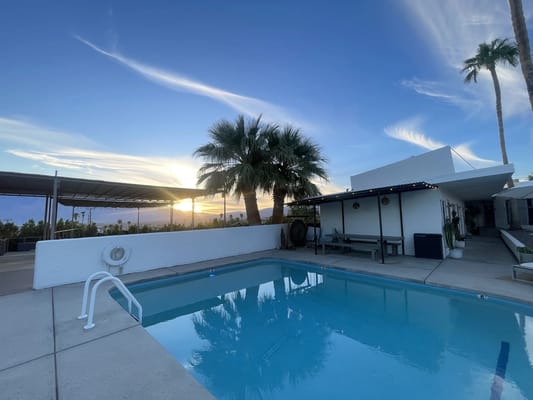 Swimming pool area with palm trees and sunset