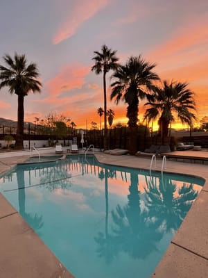 Calm sunset over a swimming pool surrounded by palm trees