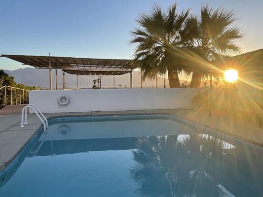 Serene outdoor pool area with palm trees and sunset