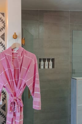 Bathroom with a pink robe and shower products
