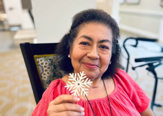 A resident holding a snowflake decoration in a cheerful pose