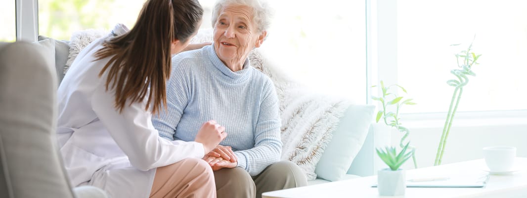 A caregiver interacting with a smiling senior in a cozy living room