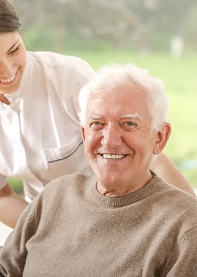 A staff member assisting a smiling senior resident