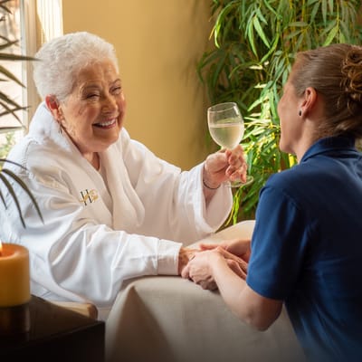 A resident enjoying a drink with a staff member in a cozy setting