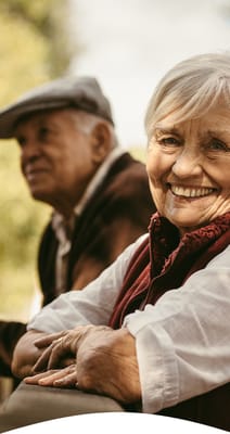 Two seniors smiling in a garden setting