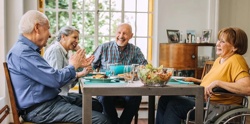 Residents enjoying a meal and conversation in a dining area.